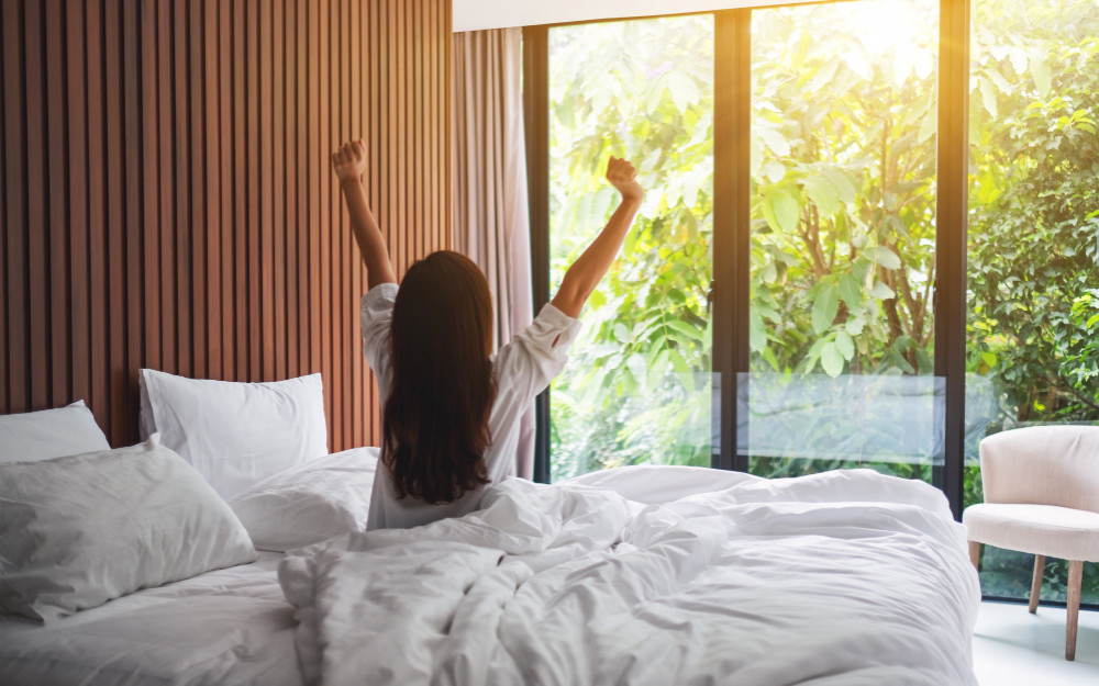 rear-view-woman-stretching-after-waking-up-morning-looking-beautiful-nature-view-outside-bedroom-window